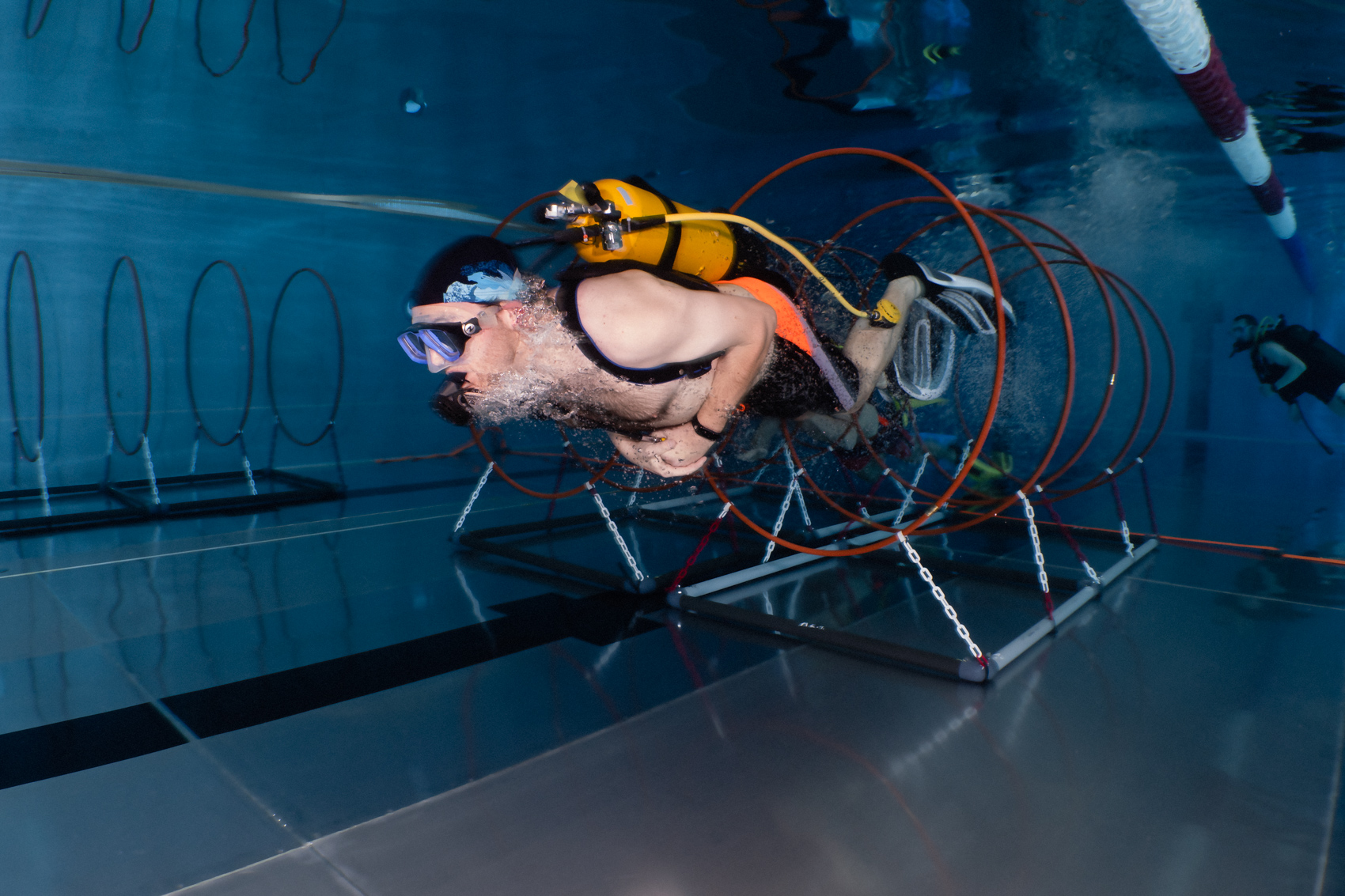 Plongeur traversant des cerceaux dans une piscine