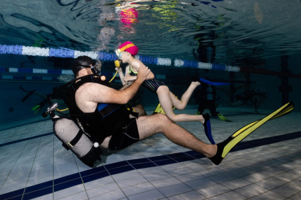 Une petite fille, accompagnée d'un moniteur, fait sont Baptême de plongée dans une piscine prés de Nancy
